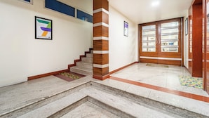 A staircase with a wooden column, a door with glass panels, and a framed poster on the wall. - Treebo Sam Residency (Coimbatore)