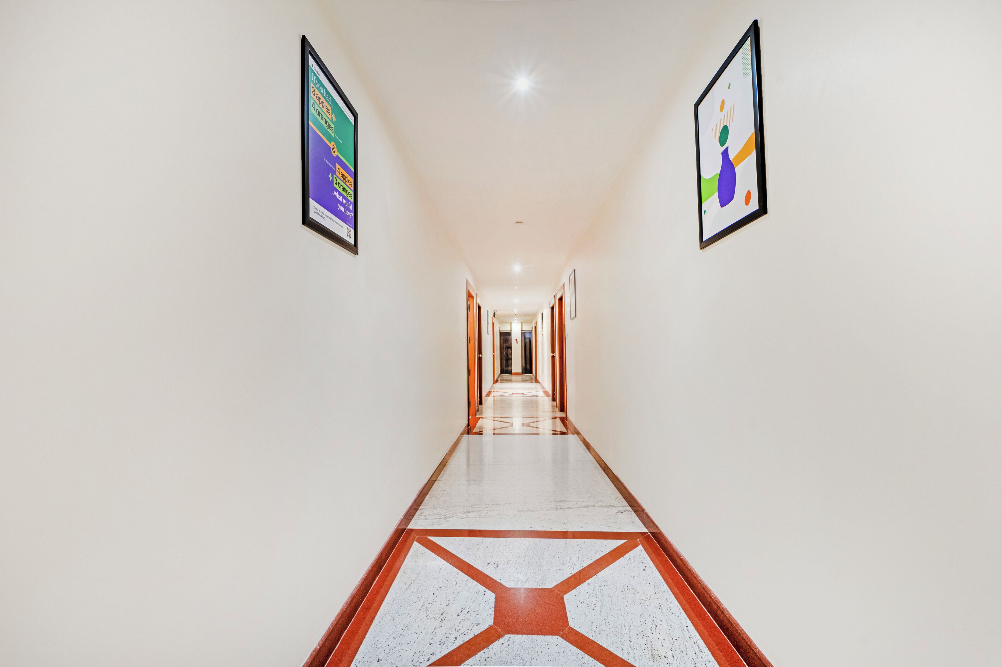 A long, narrow hallway with a polished floor and framed artwork on the walls.