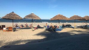 A beach with thatched umbrellas and lounge chairs. - Ally Beach Boutique Hotel Hoian (Da Nang)