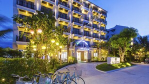 A hotel with a modern design, featuring multiple balconies and a well-lit entrance. - Ally Beach Boutique Hotel Hoian (Da Nang)