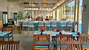A restaurant with a bar area, wooden chairs, and tables set for dining. - Ally Beach Boutique Hotel Hoian (Da Nang)