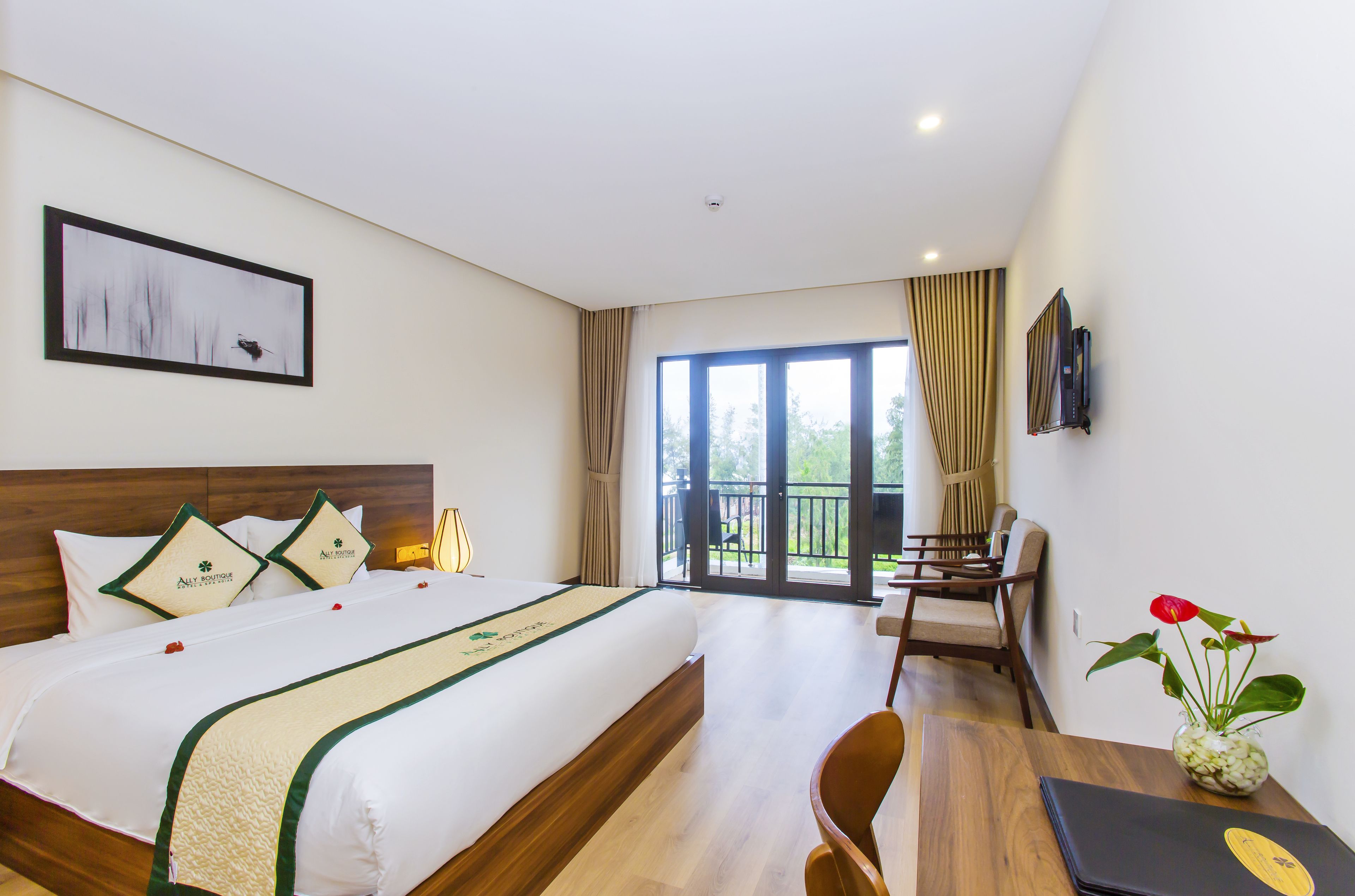A hotel room with a large bed, a desk, a chair, a TV, a window with curtains, and a balcony.