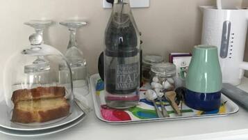 A kitchen counter with a bottle of water, a glass jar, a green mug, and a plate with bread.
