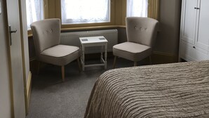 Una habitación de hotel con una cama, dos sillones, una mesita y un radiador.