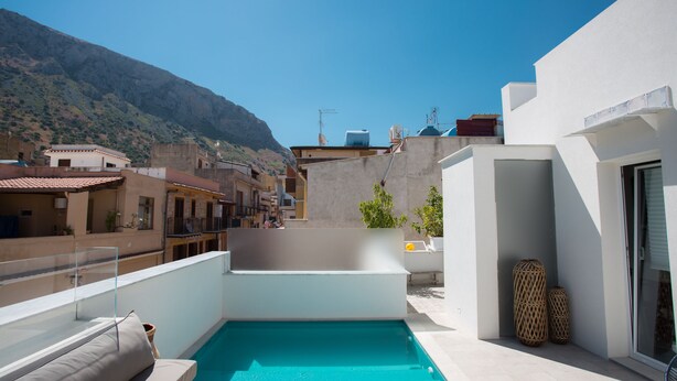 Una piscina en la azotea con vistas despejadas de los edificios circundantes y una montaña al fondo.