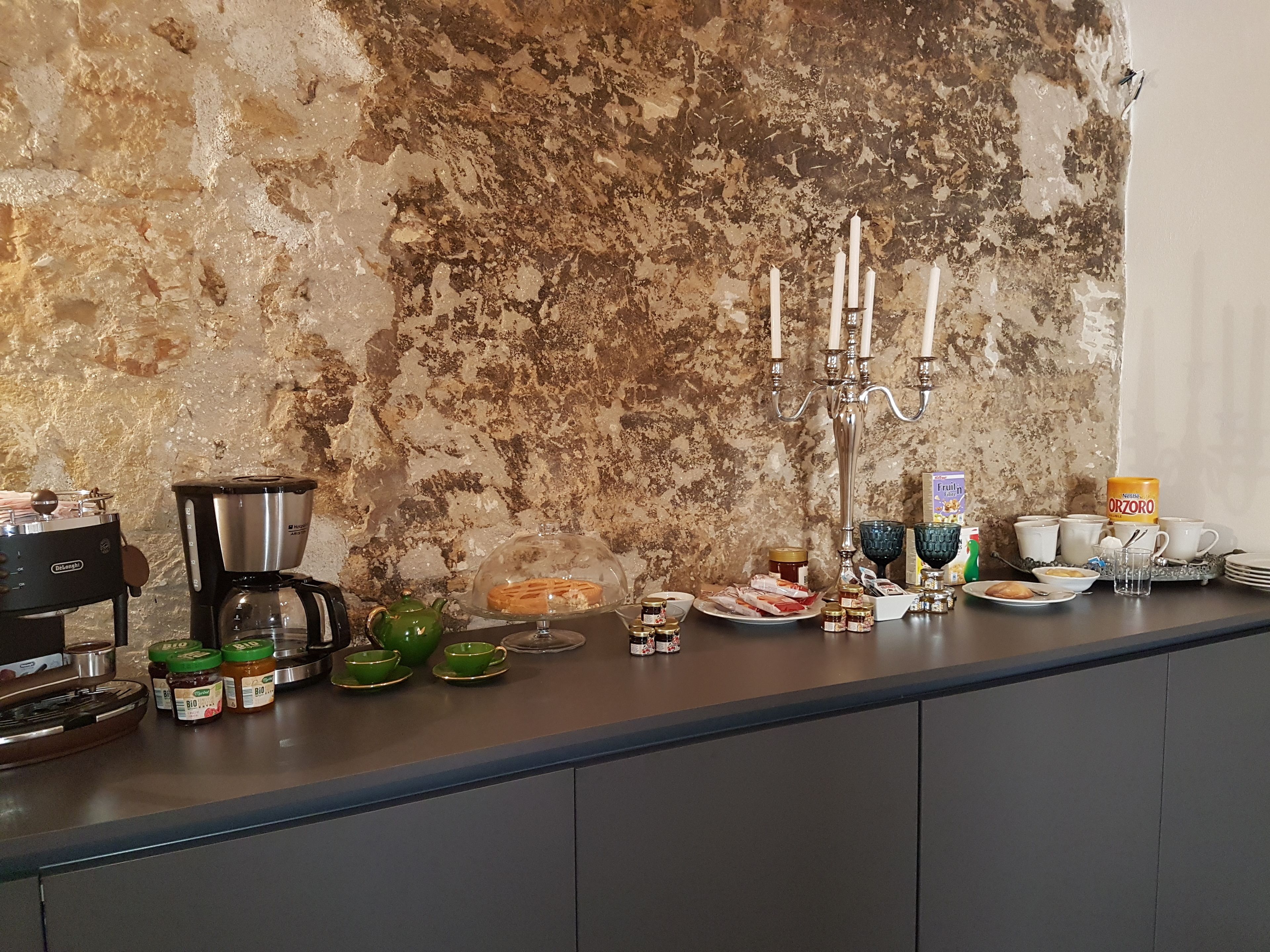 Una encimera de cocina con una cafetera, frascos, una tetera y un candelabro.