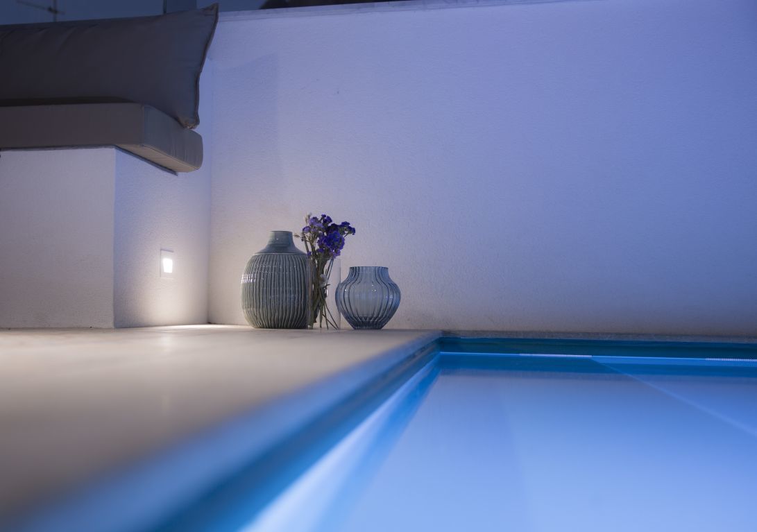 Un interior moderno con piscina, dos jarrones y una lámpara de pared.