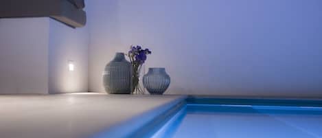 A modern interior with a pool, two vases, and a wall-mounted light fixture.