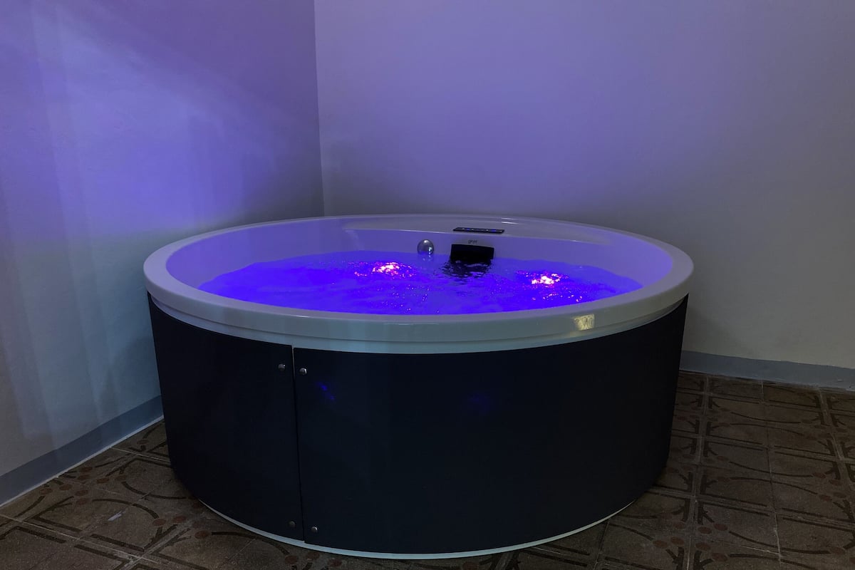 Un jacuzzi con panel de control y pantalla digital, rodeado de piso de baldosas y paredes lisas.