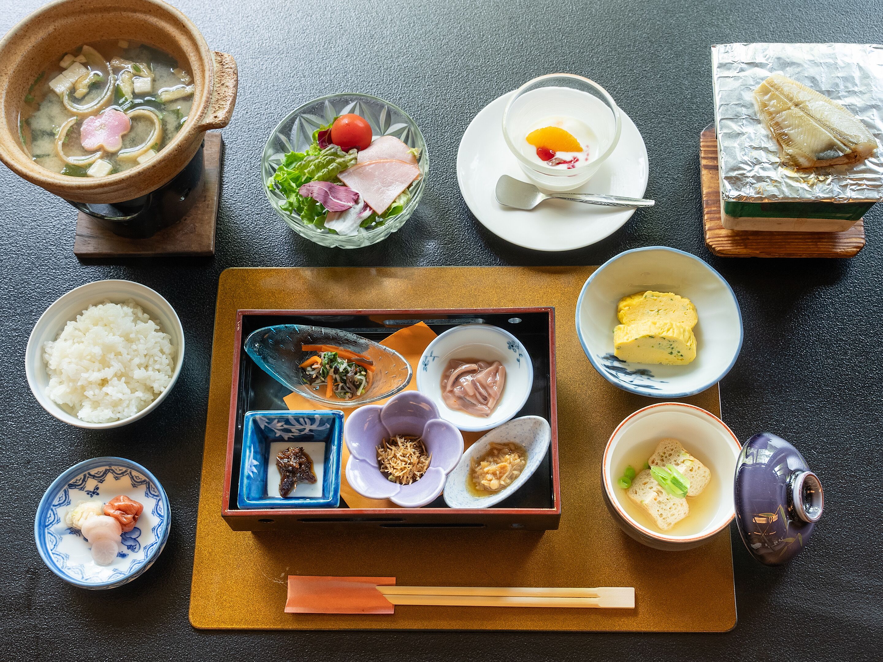 A traditional Japanese meal setup with various dishes including rice, soup, sashimi, and pickled vegetables.
