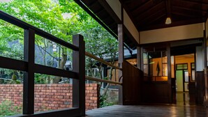 A wooden deck with a glass railing overlooking a brick wall and greenery. - Livemax Resort Yuhigaura Kitu Onsen (Kyotango)