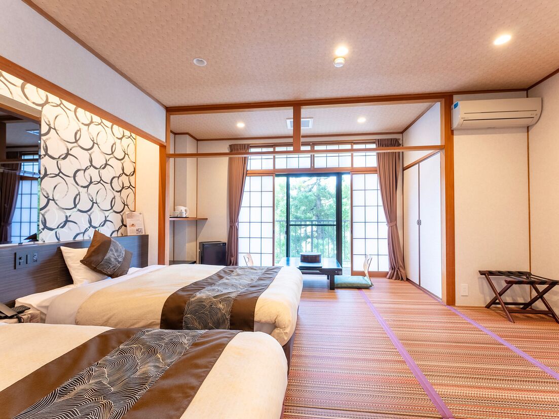 A hotel room with two beds, a tatami mat floor, a sliding door, and a view of greenery outside.