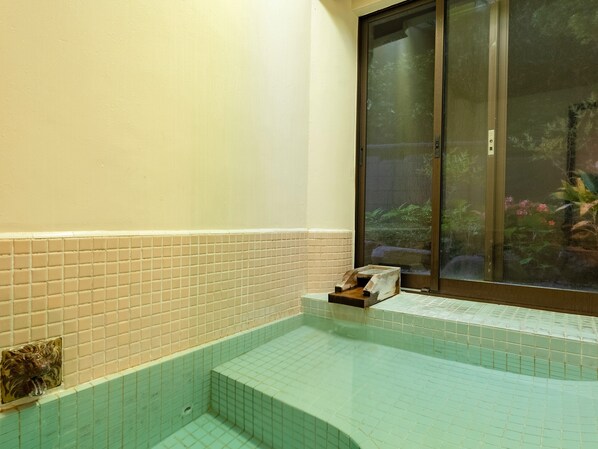 A bathroom with a bathtub, tiled walls, and a window with a view of greenery. - Livemax Resort Yuhigaura Kitu Onsen (Kyotango)