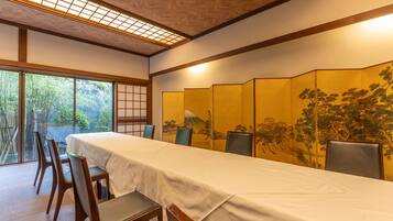 Habitació tradicional japonesa amb sòl de tatami, una taula baixa amb estovall i una porta corredissa amb una pintura de bosc.
