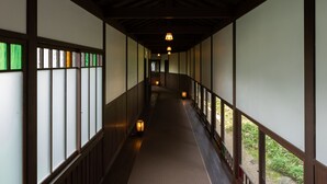 A corridor with wooden beams and tatami mat flooring, leading to a room with a view of greenery. - Livemax Resort Yuhigaura Kitu Onsen (Kyotango)