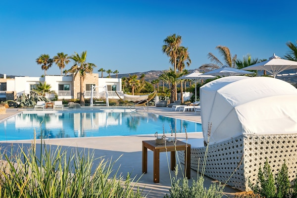 Una piscina al aire libre, sombrillas, tumbonas