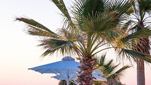 A serene outdoor seating area with a hanging chair, a table, and a large umbrella. - White Pearls Luxury Suites - Adults Only (Kos)