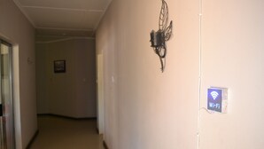 A hallway with a Wi-Fi sign, a decorative wall piece, and a framed picture on the wall. - Honeybed Lodge (Lusaka)