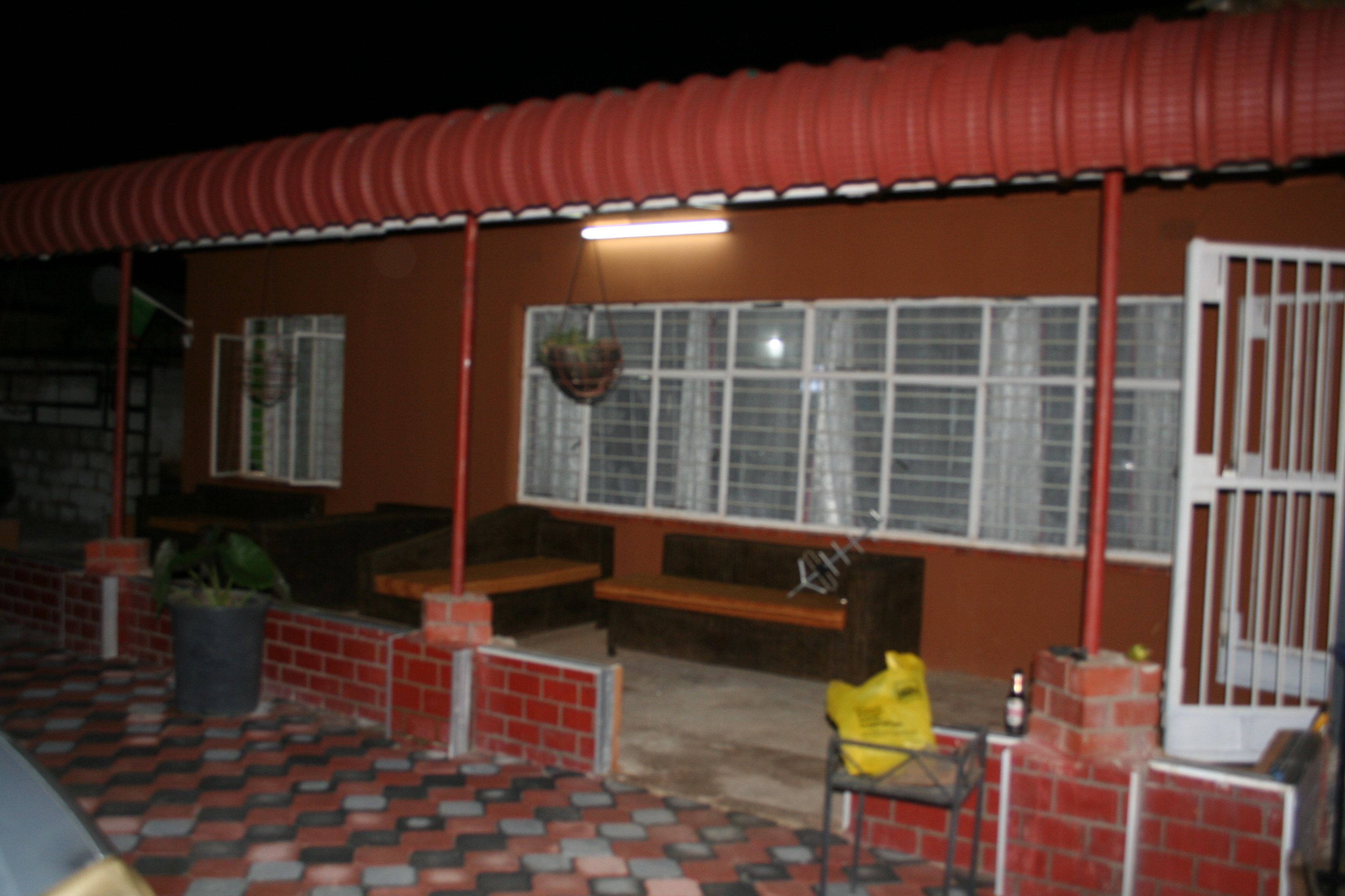Un edificio con techo rojo, pared de ladrillo y ventana con reja de metal.