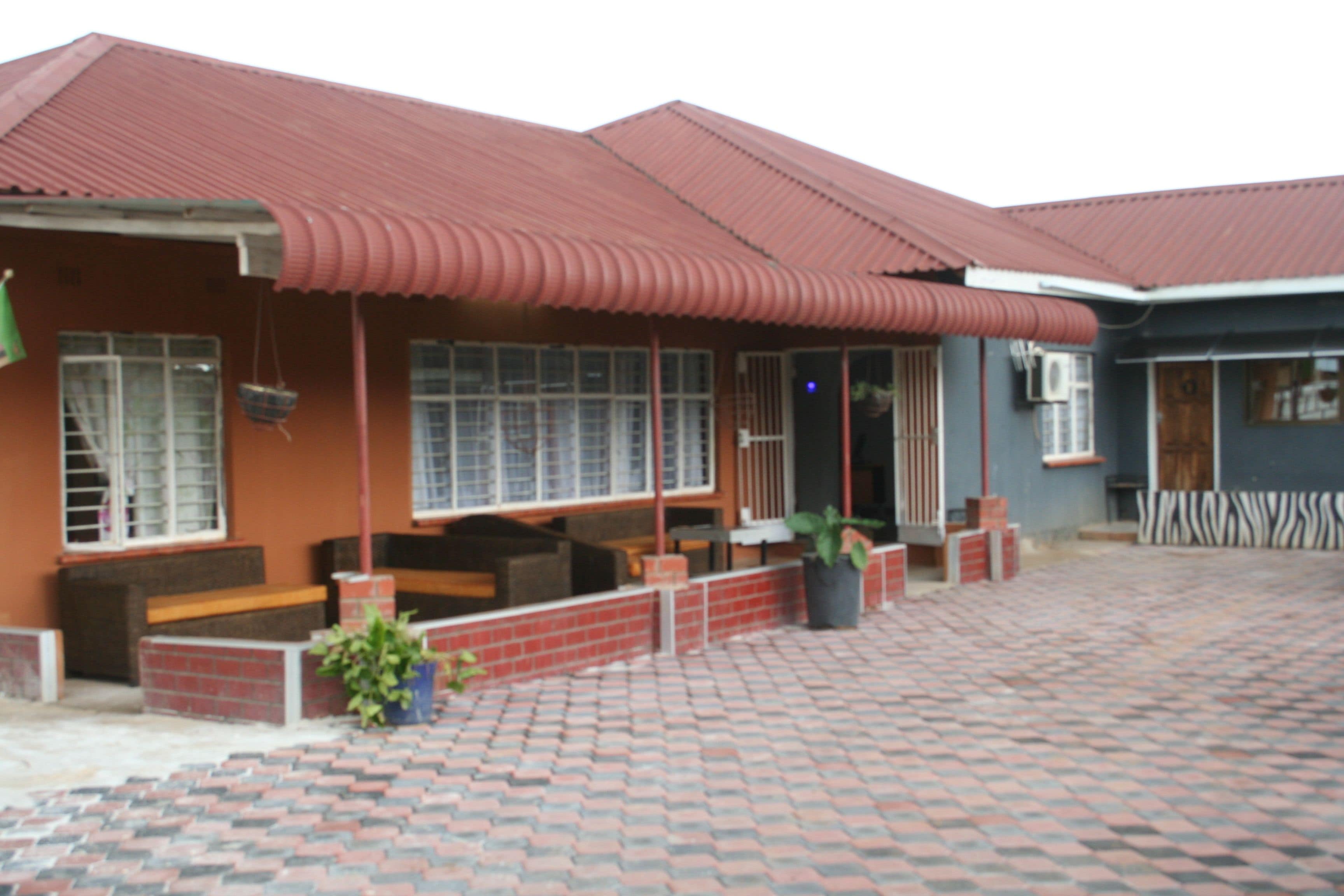 Un edificio con techo rojo, paredes de ladrillo y un patio empedrado.