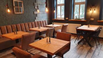 A restaurant with wooden tables and benches, stone wall decor, and large windows.