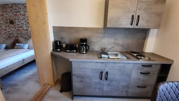 A compact kitchenette with a sink, coffee maker, toaster, and cabinets.