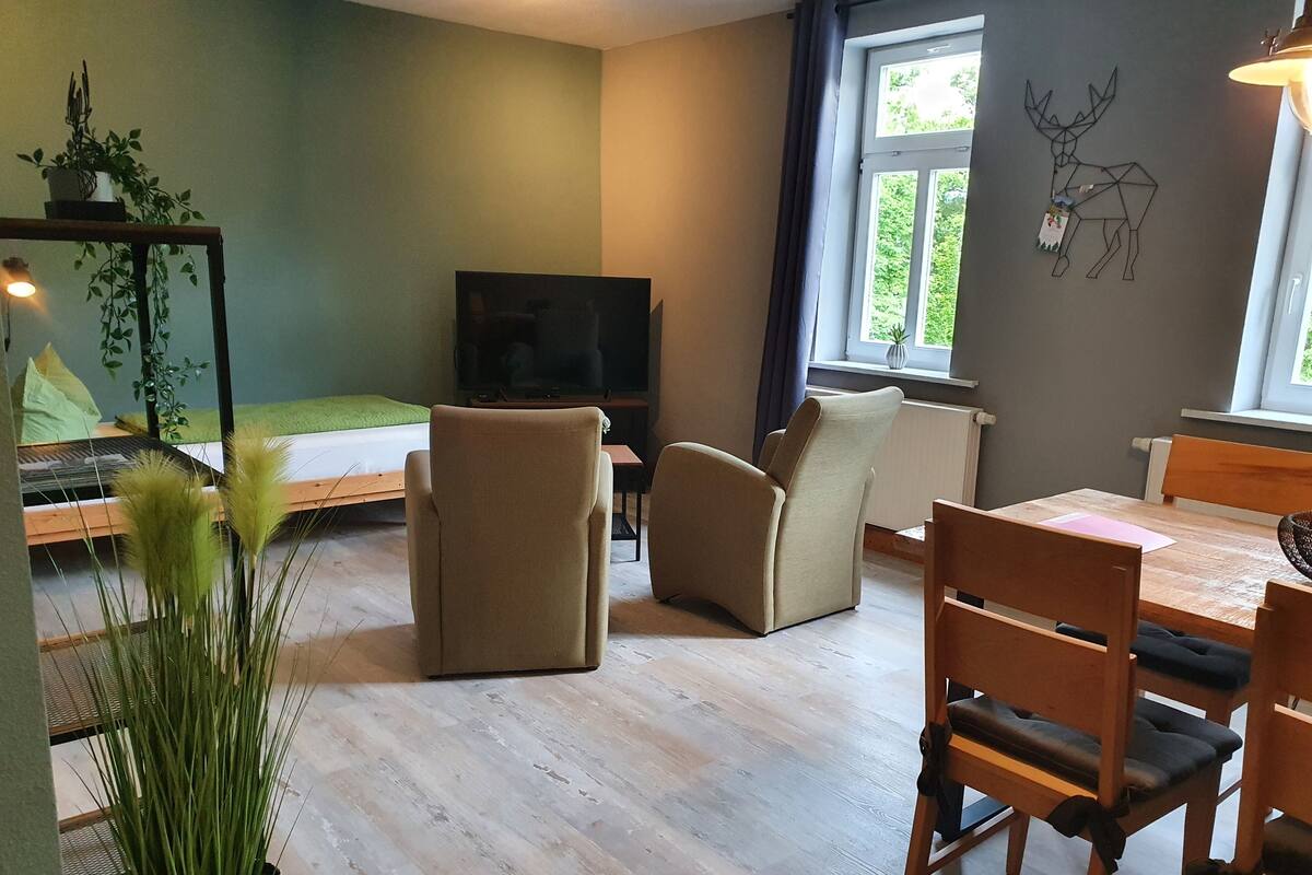 Un salon moderne comprenant un canapé, des fauteuils, une table à manger et un téléviseur.