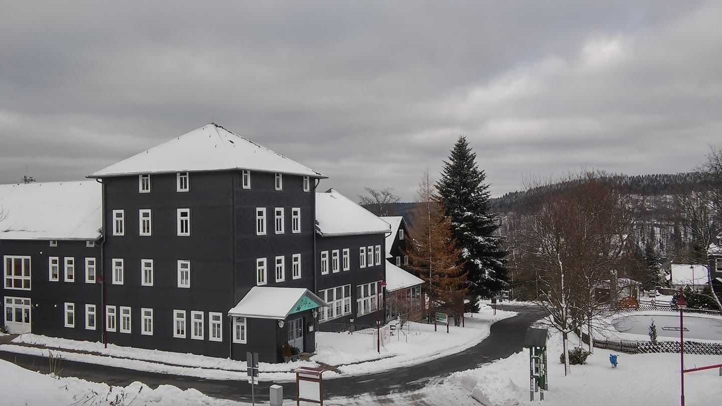 Un edificio de varios pisos con techo nevado y toldo verde.