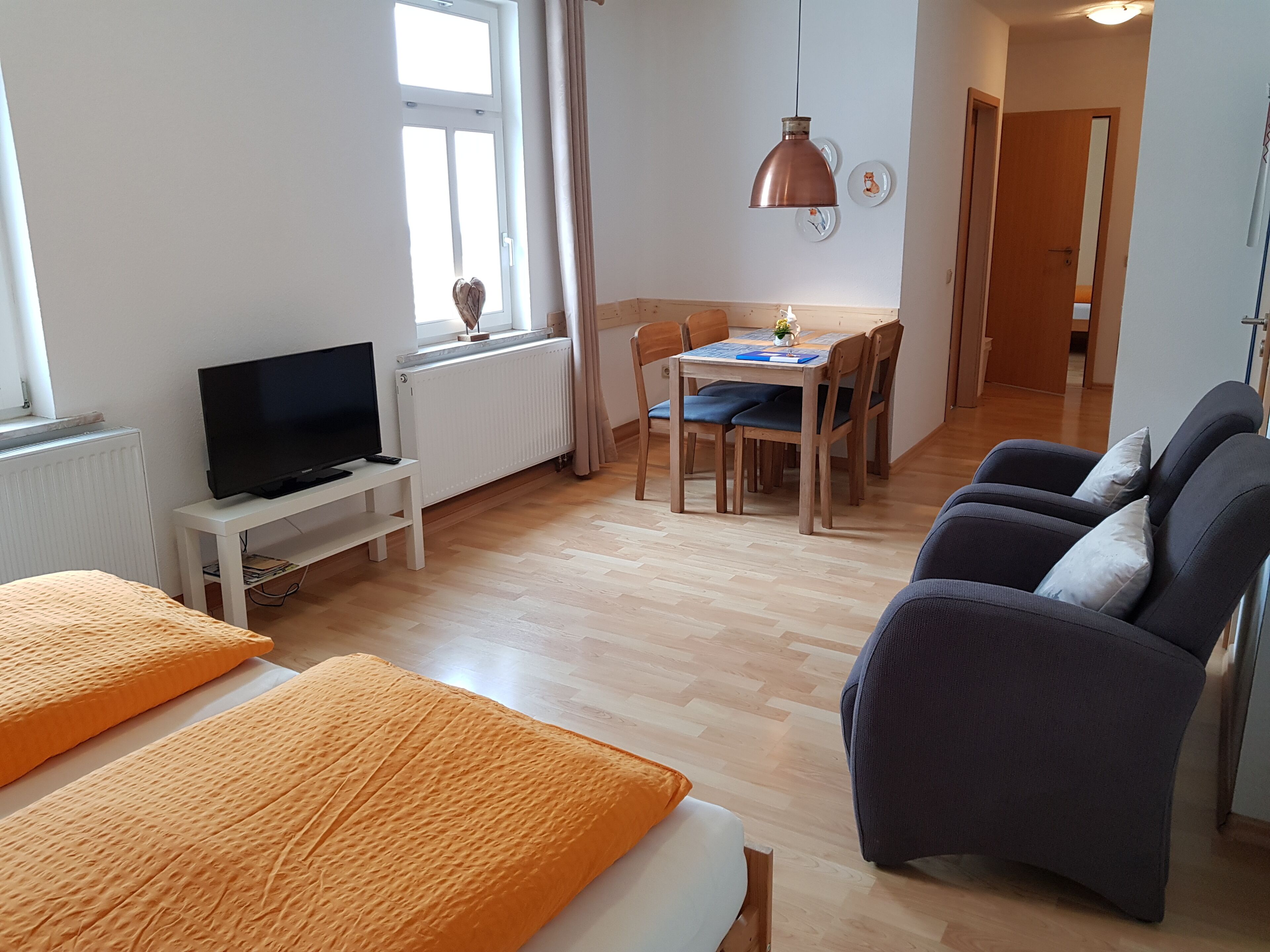Een hotelkamer met een bed, een televisie, een eettafel met stoelen en een bank.