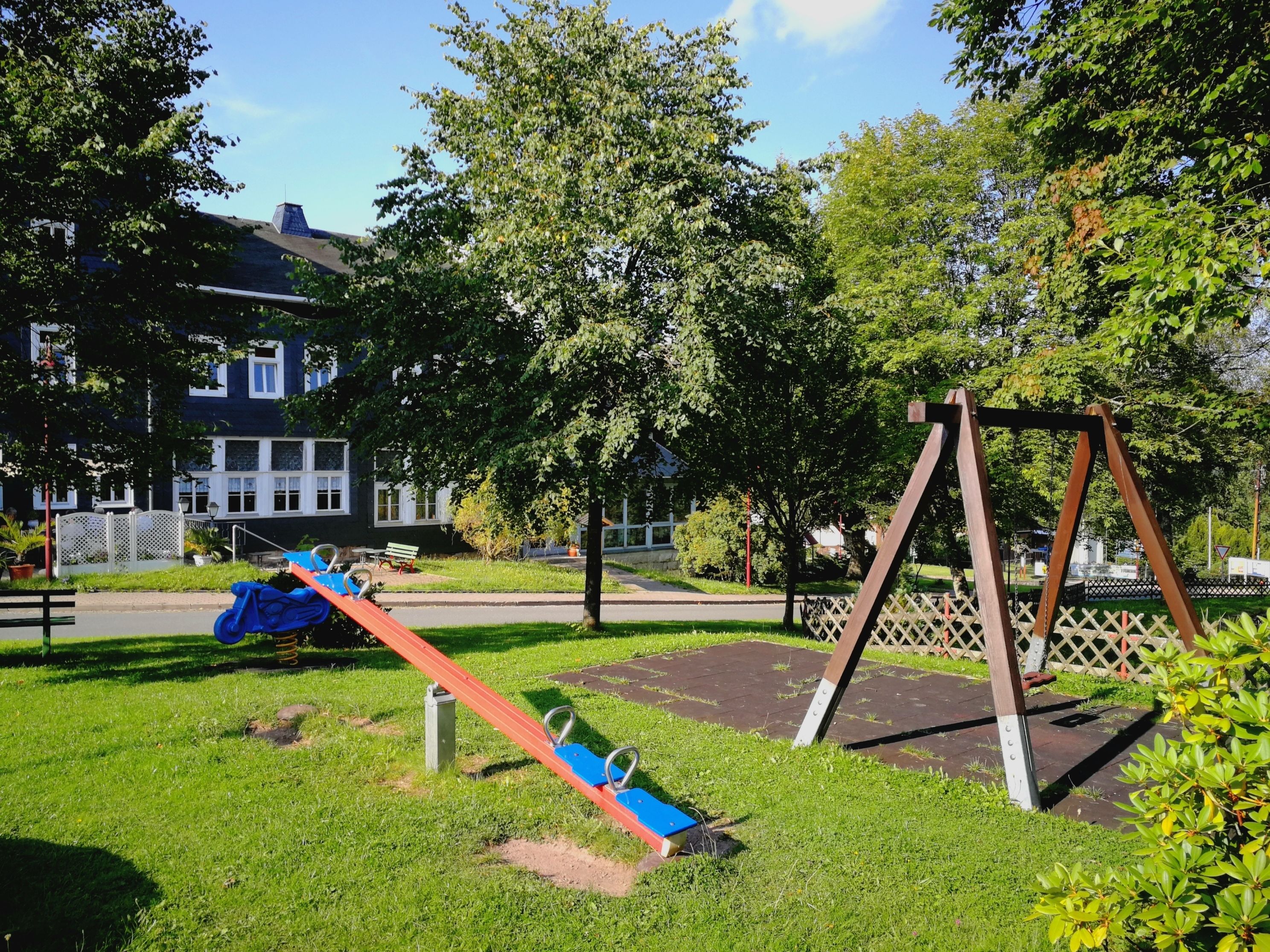 A playground with swings and a slide in a park area.