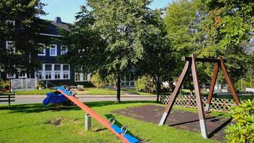 A playground with swings and a slide in a park area.