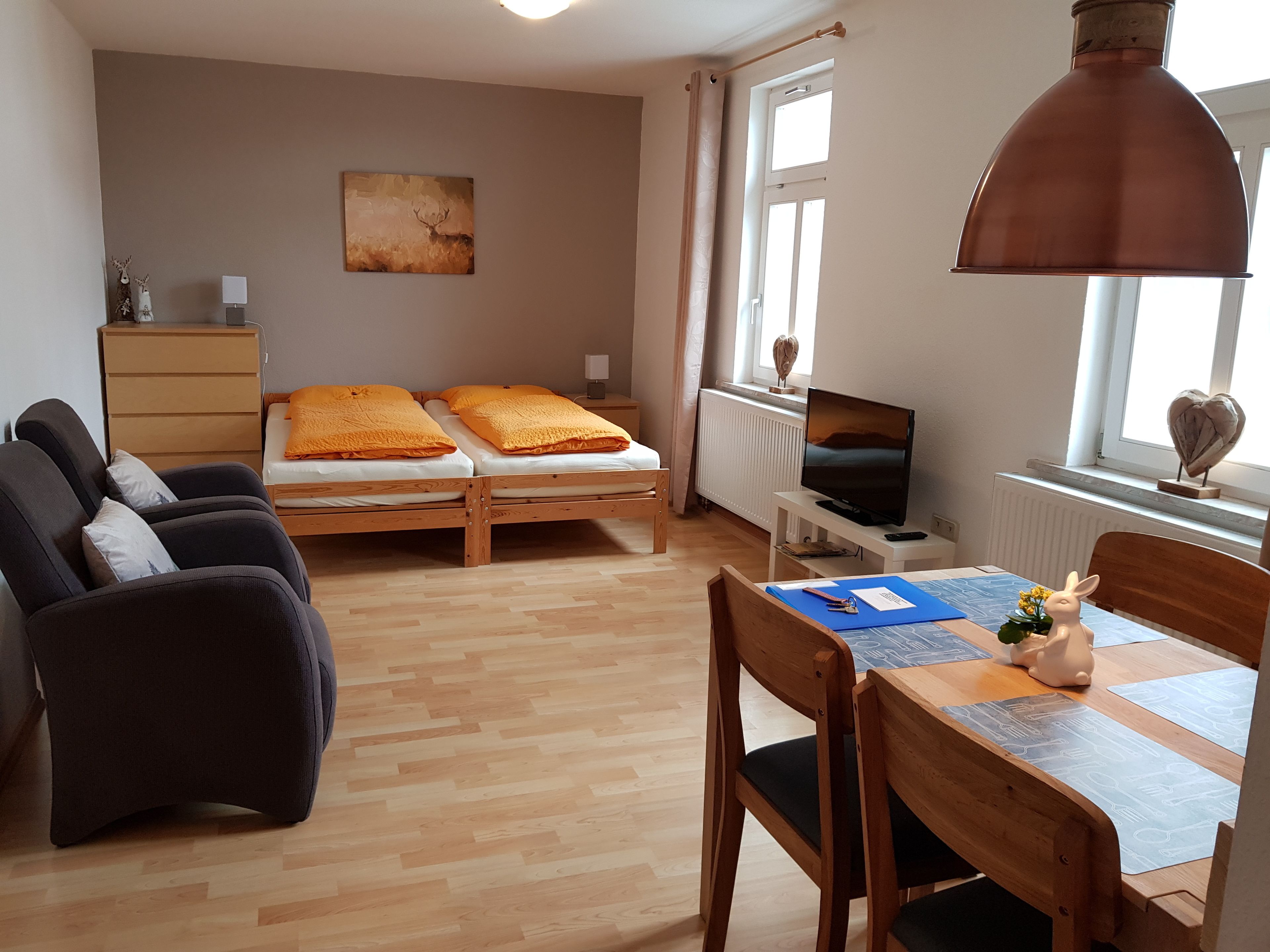 A room with two beds, a desk, a chair, a television, and a window.
