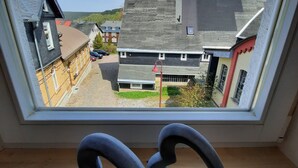 En utsikt från ett fönster över ett bostadsområde med hus, en klar himmel och ett trägolv inuti.