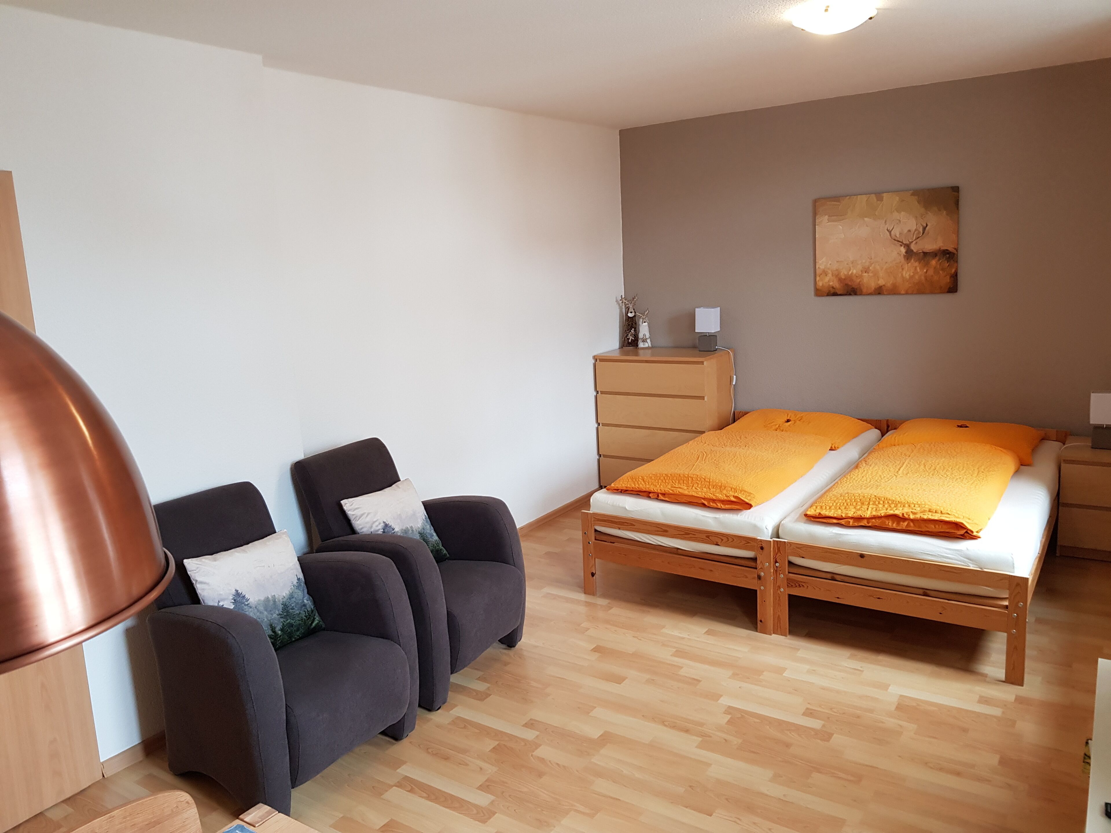 Una habitación con una cama, dos sillas, un aparador y un cuadro en la pared.