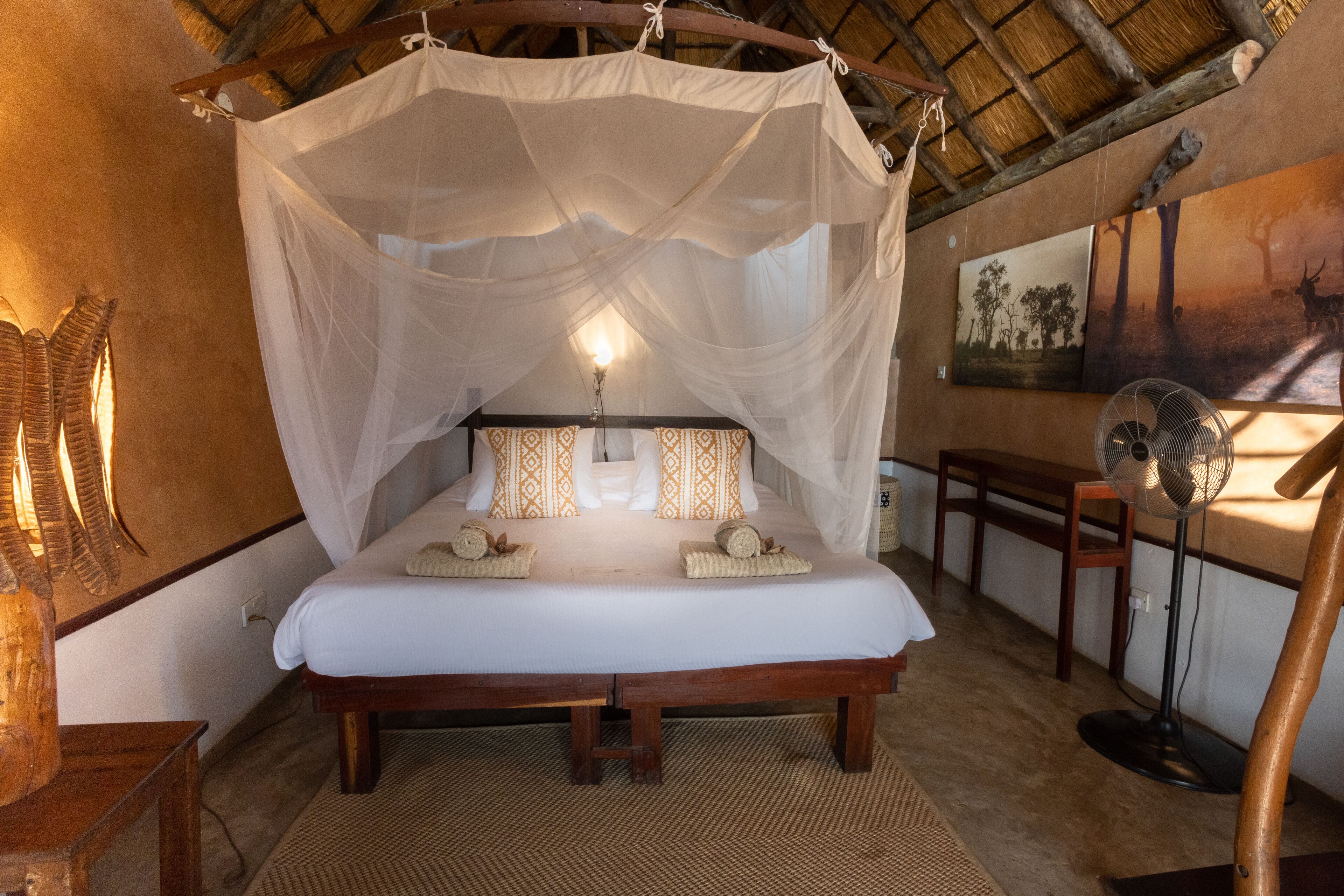 Un lit à baldaquin, une lampe de chevet et des coussins à motifs.