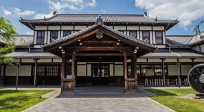 Un edificio japonés tradicional con un pabellón de entrada de madera, tejados de tejas y un camino de piedra que conduce a la entrada.