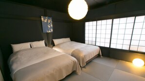 A room with two beds, a wall-mounted TV, and a large window with grid blinds. - Hosta Nijo Aoi (Kyoto)