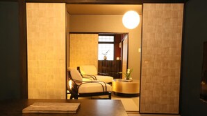 A room with a wooden table, two chairs, a round table with a vase, and a large window with a view. - Hosta Nijo Aoi (Kyoto)