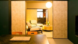 A room with a wooden table, two chairs, a round yellow side table, and a small plant. - Hosta Nijo Aoi (Kyoto)