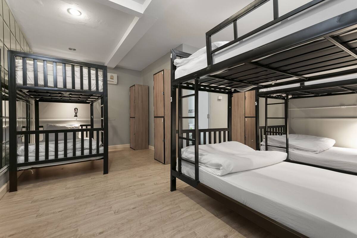 Habitación con literas, suelo de madera, armario y una pequeña cocina.