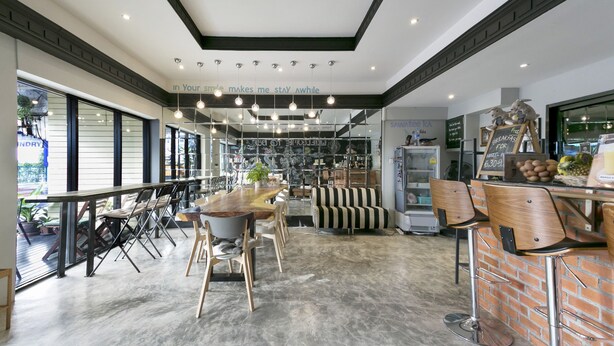 A modern cafe with a long counter, seating area, and a view of the street. - 1989 Sukhumvit Bangkok - Hostel (Bangkok)