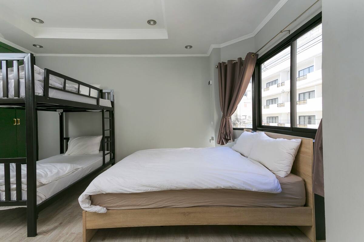 Una habitación con una cama litera, una cama individual y una ventana con cortinas.