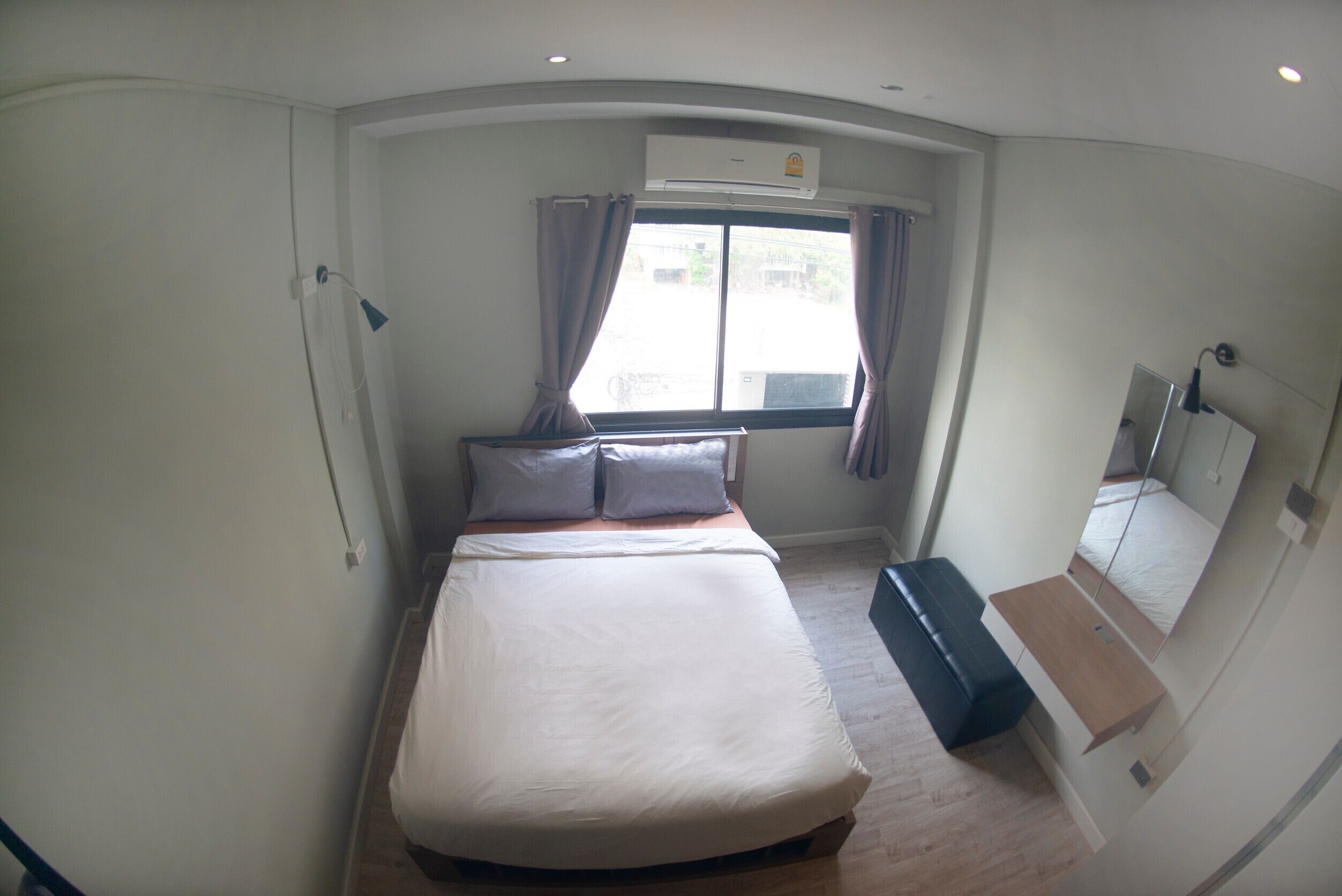 Une chambre à coucher avec un lit, une fenêtre avec des rideaux, un appareil de climatisation et une table de chevet.