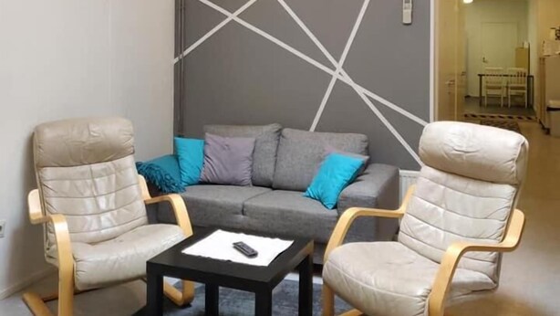 A modern living room with a grey sofa, two beige armchairs, and a black coffee table. - Hostel Racuna (Kokkola)