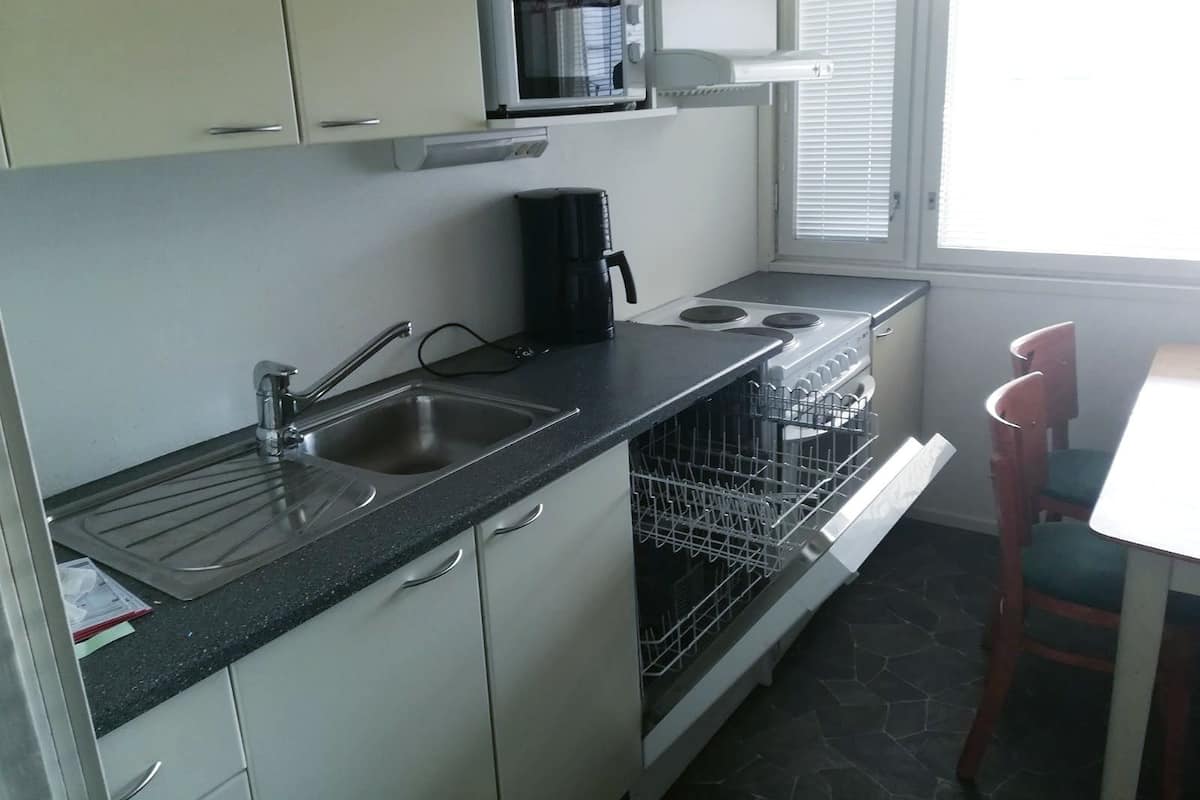 A compact kitchen with a sink, stove, microwave, and a dishwasher.