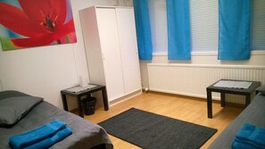A room with a bed, a small table, a wardrobe, and a radiator.
