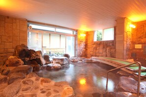 A hot spring area with a stone wall, a wooden deck, and a metal ladder. - Liberty resort AMAGISO (Kawazu)