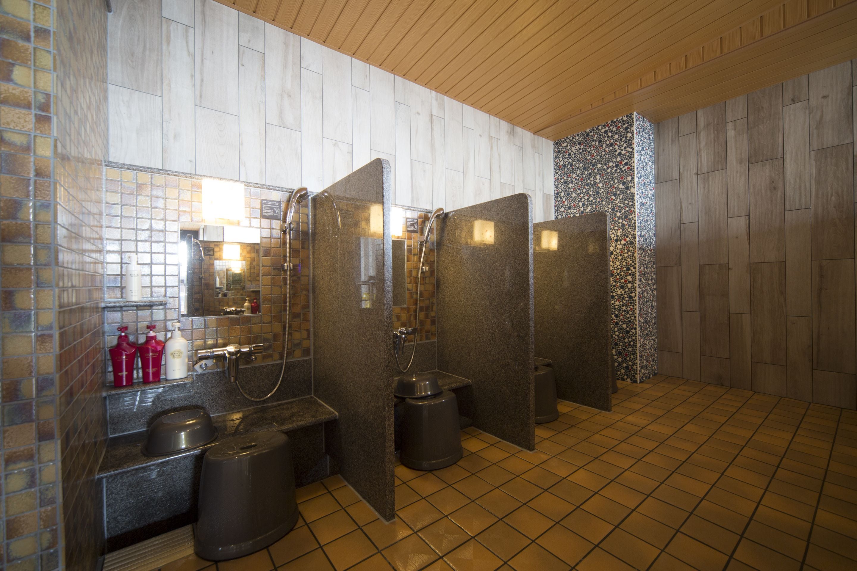 A modern bathroom with a tiled floor, a sink with a mirror, and a shower area.