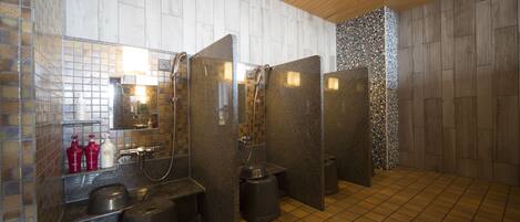 A modern bathroom with a tiled floor, a sink with a mirror, and a shower area.