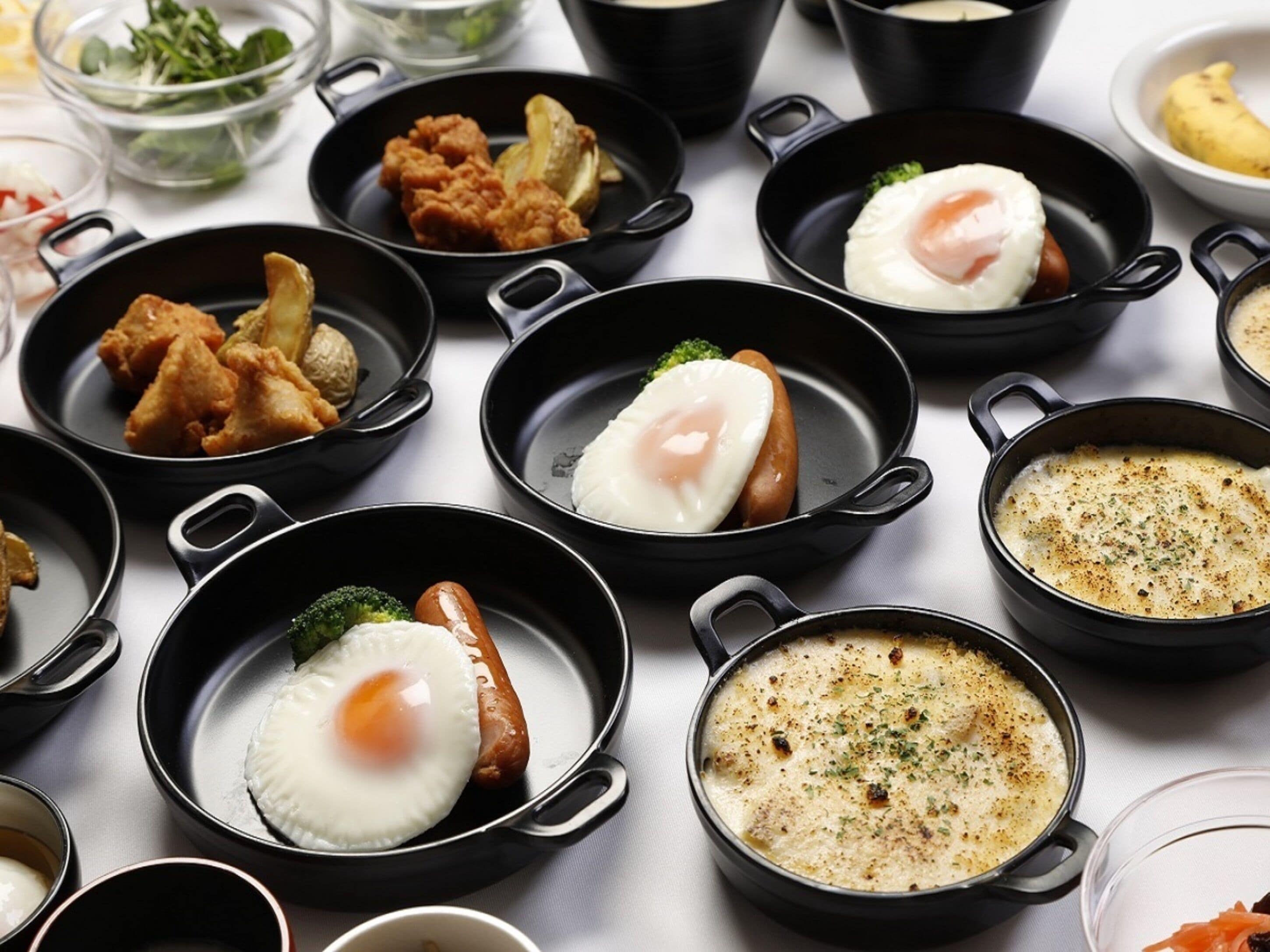 A variety of dishes in black pans on a table.